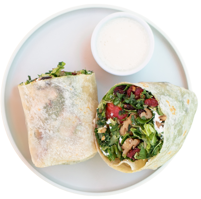 Half-eaten wrap with vegetables on a white plate with a white background